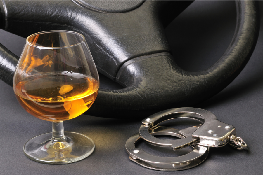 alcohol, steering wheel and handcuffs beside eachother, indicating drunk driving has consequences