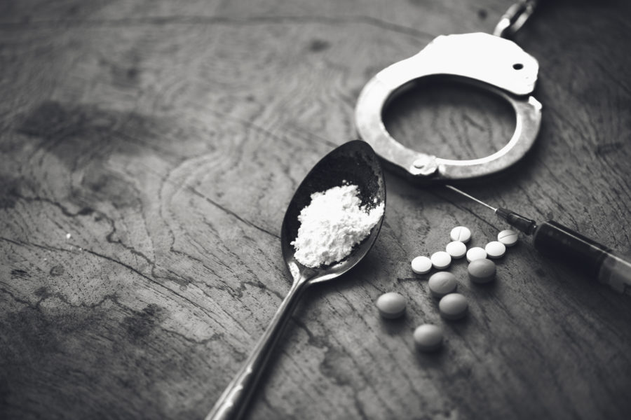 Drug syringe and cooked heroin on spoon and handcuffs