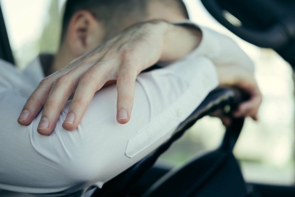 Stressed man experiencing road rage resting head on steering wheel